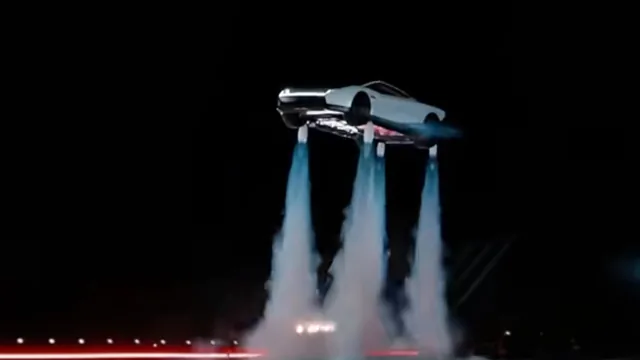 Roadster Tesla en l’air au-dessus de jets bleutés et de fumée, de nuit, lors de la démonstration