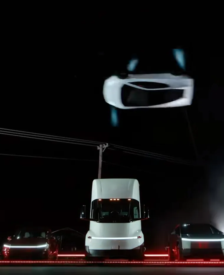Vue de dessous du véhicule passant au-dessus d’un camion Tesla Semi, avec des lignes électriques en arrière-plan